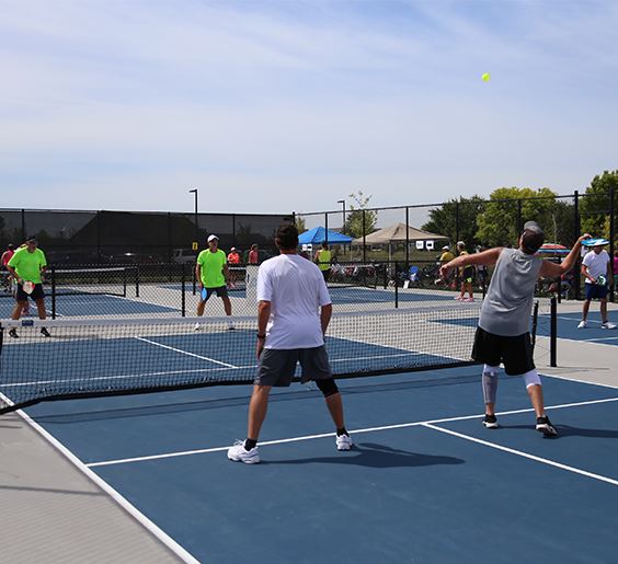 a man serving during a pickleball game at fox creek park