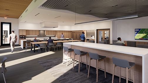 Break room with long counter and stools, kitchen, tables and chairs and tv on wall