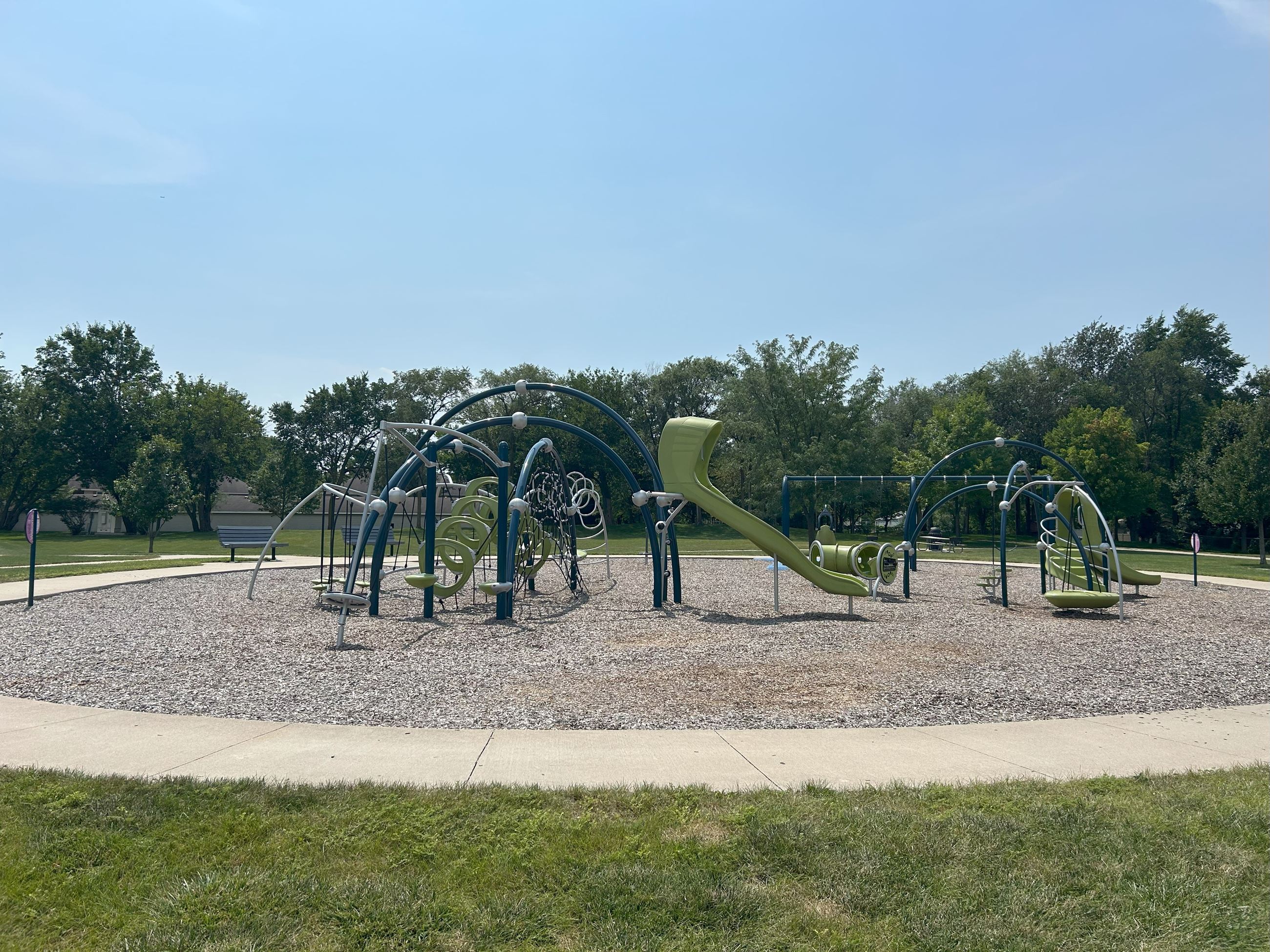 Wide shot of the playground which includes two slides, climbing structures and swings.