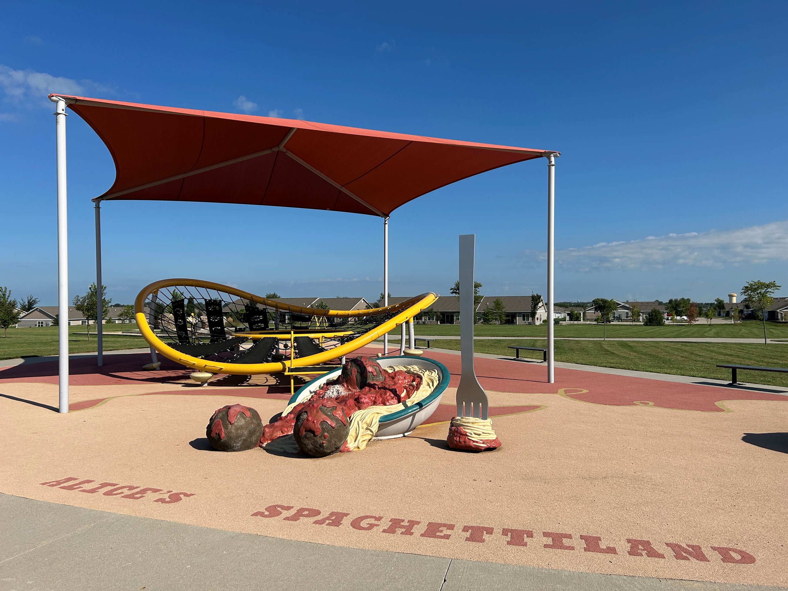 Wide view of the spaghetti park including the play structure and shaded area.