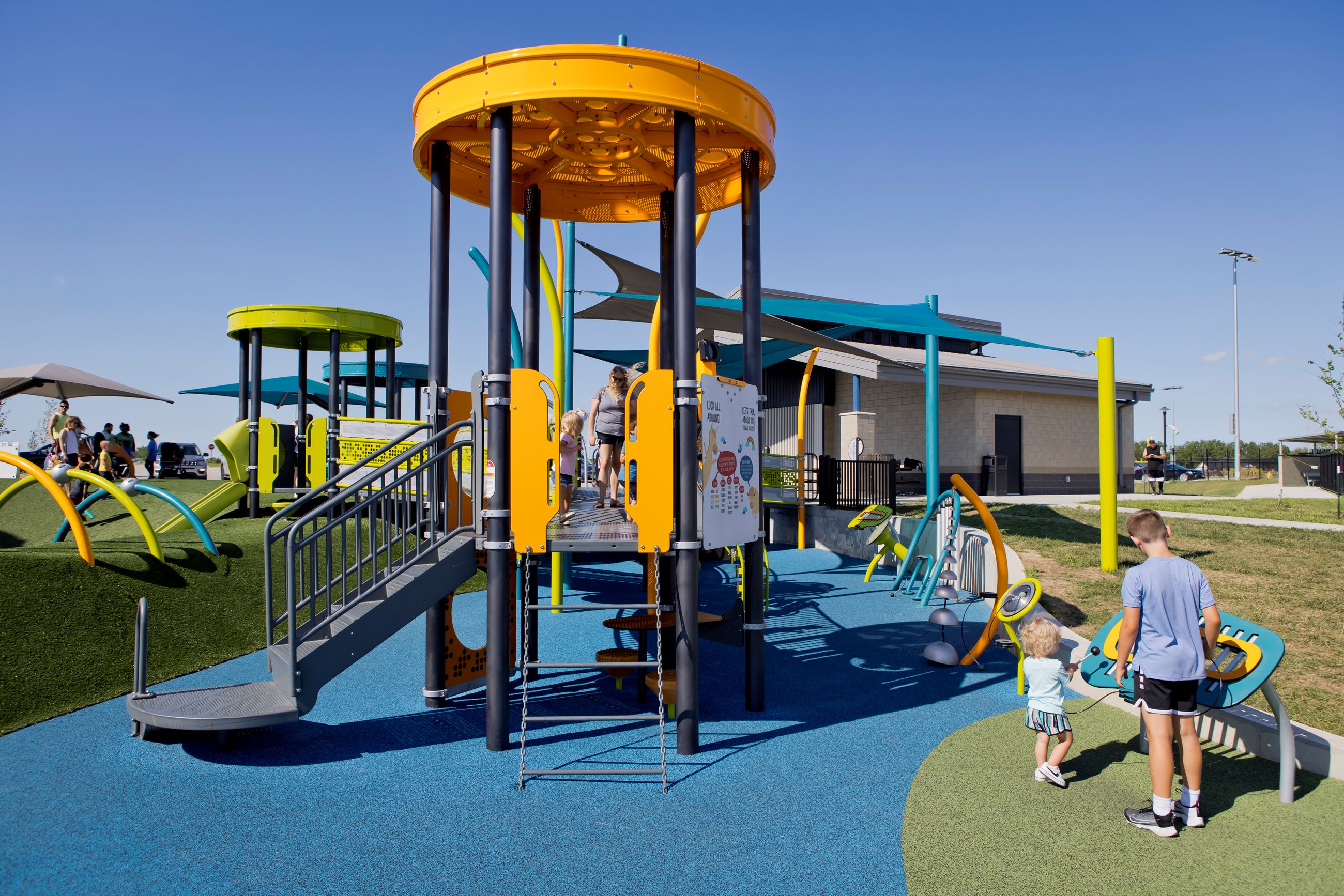 children play at the music station next to the smaller play structure for young children